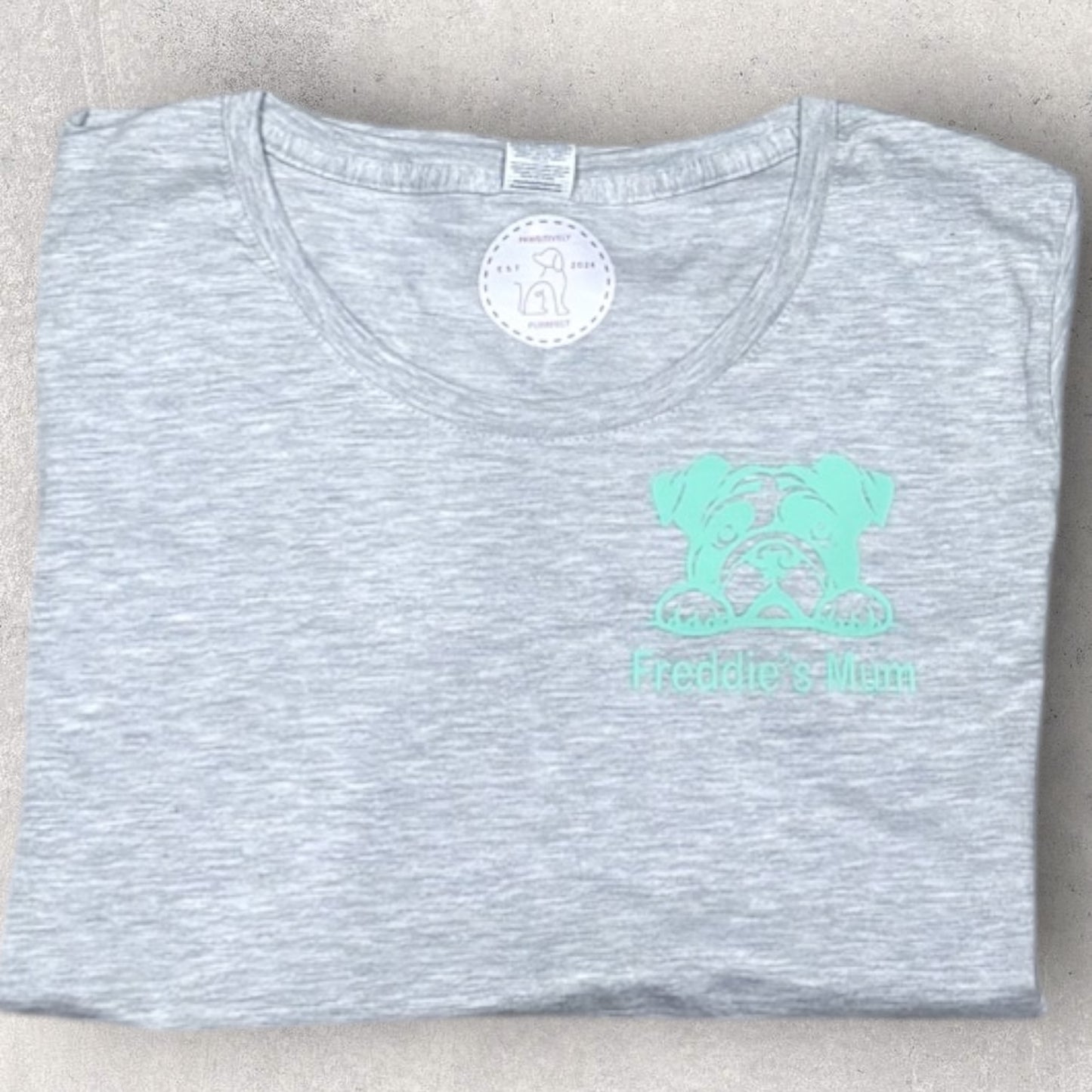 Gray t-shirt with a green logo on a beige surface