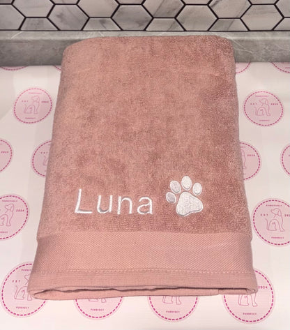 Brown towel with 'Luna' and a paw print on a patterned background