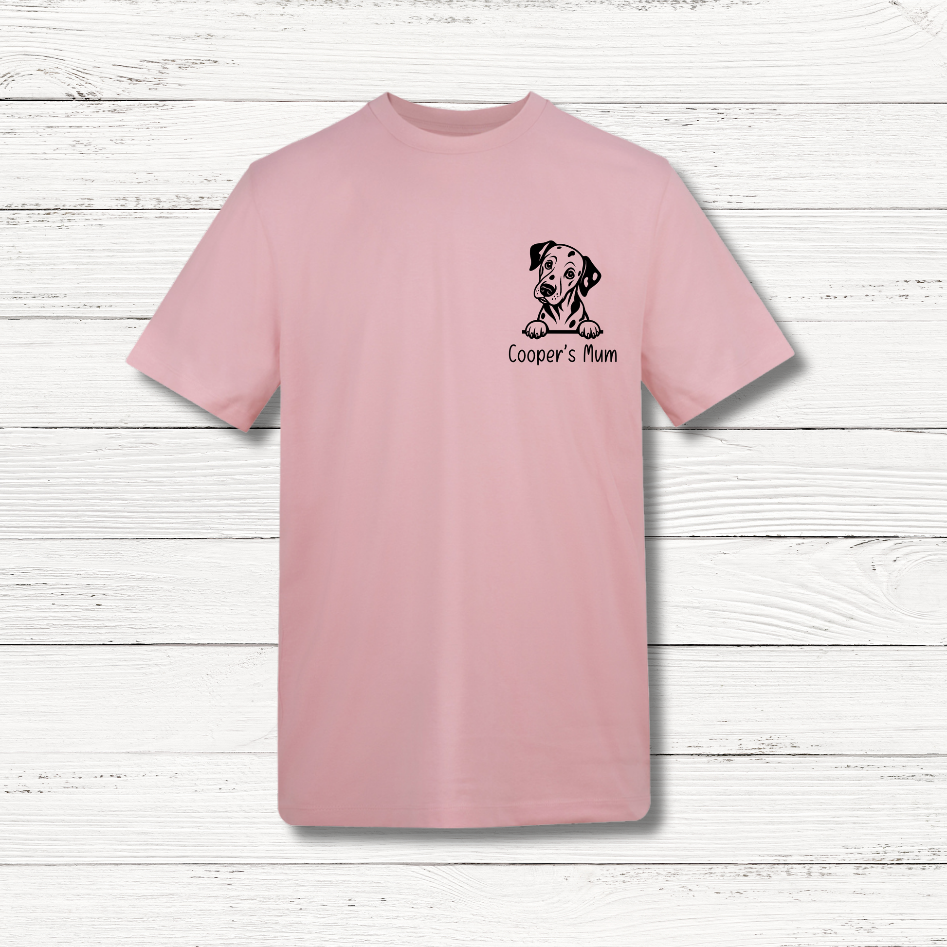 Pink t-shirt with a dog illustration and text on a wooden surface