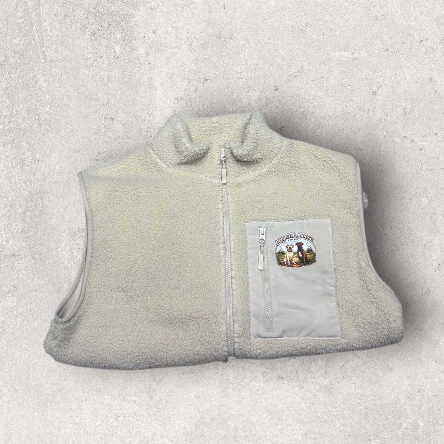 Light gray fleece gilet with a patch on a light gray background