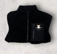 Black fleece vest with a small pouch on a light gray background