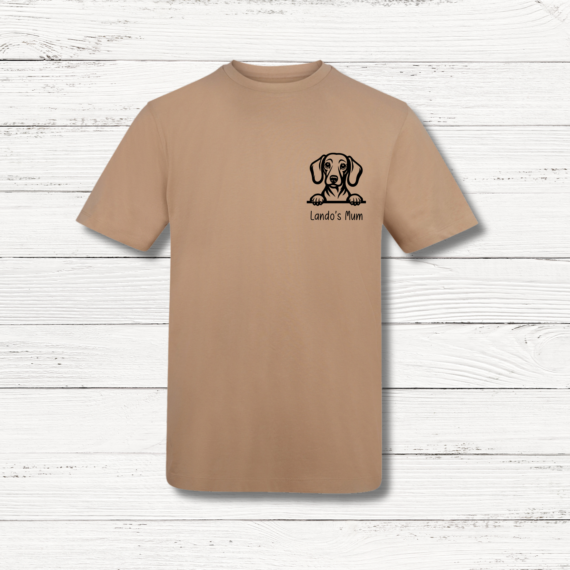 Beige t-shirt with a dog illustration and text on a wooden surface