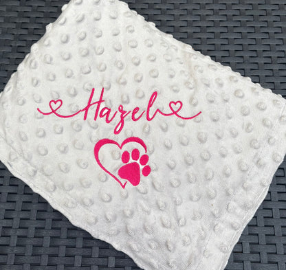 light grey textured blanket with pink text and heart design on a dark woven surface