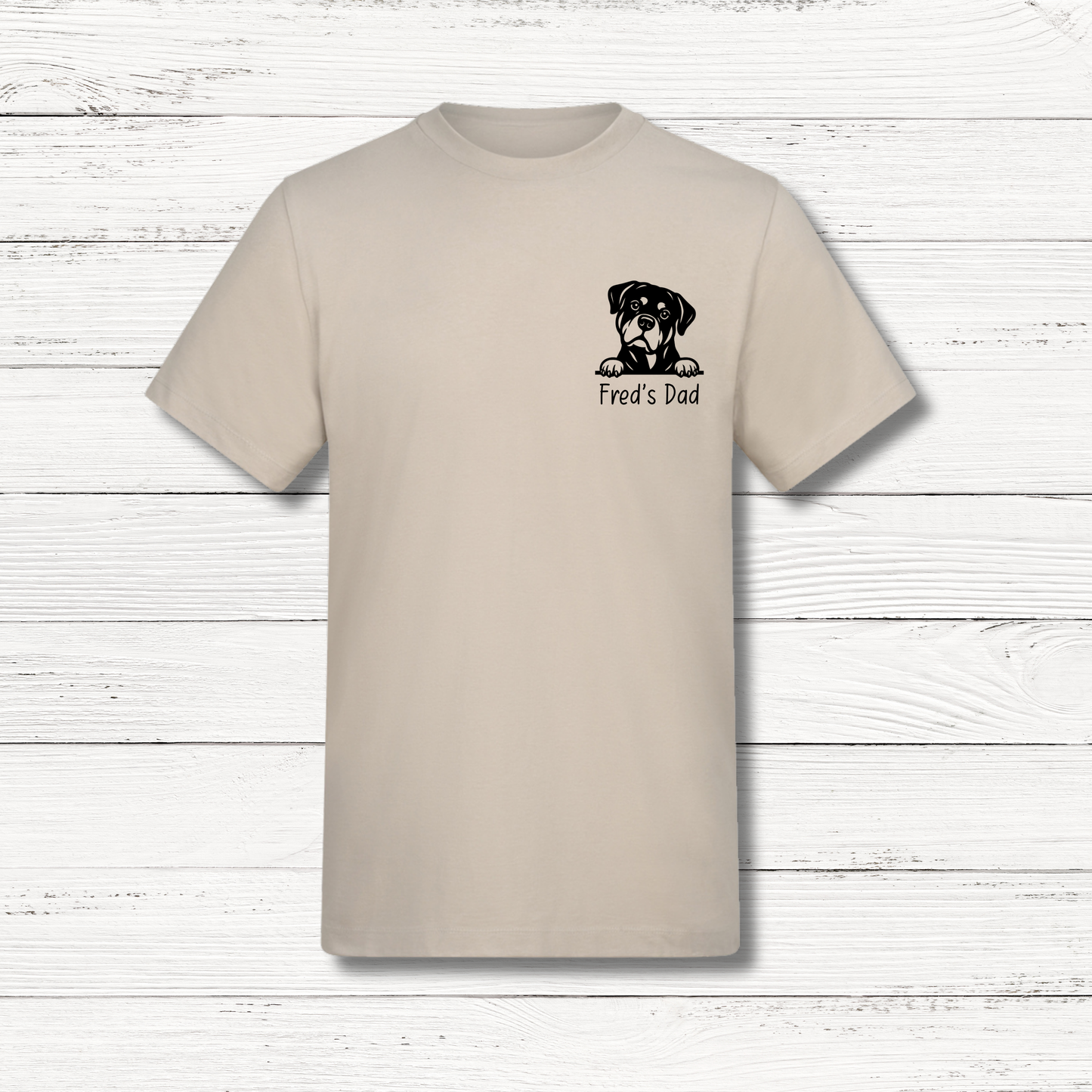Beige t-shirt with a dog graphic and text on a wooden surface
