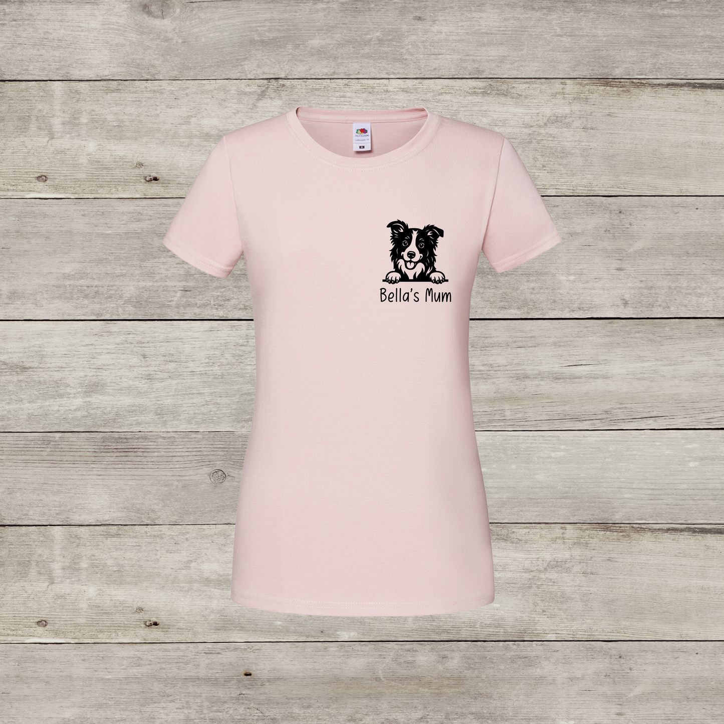 Pink t-shirt with a dog illustration and text on a wooden surface