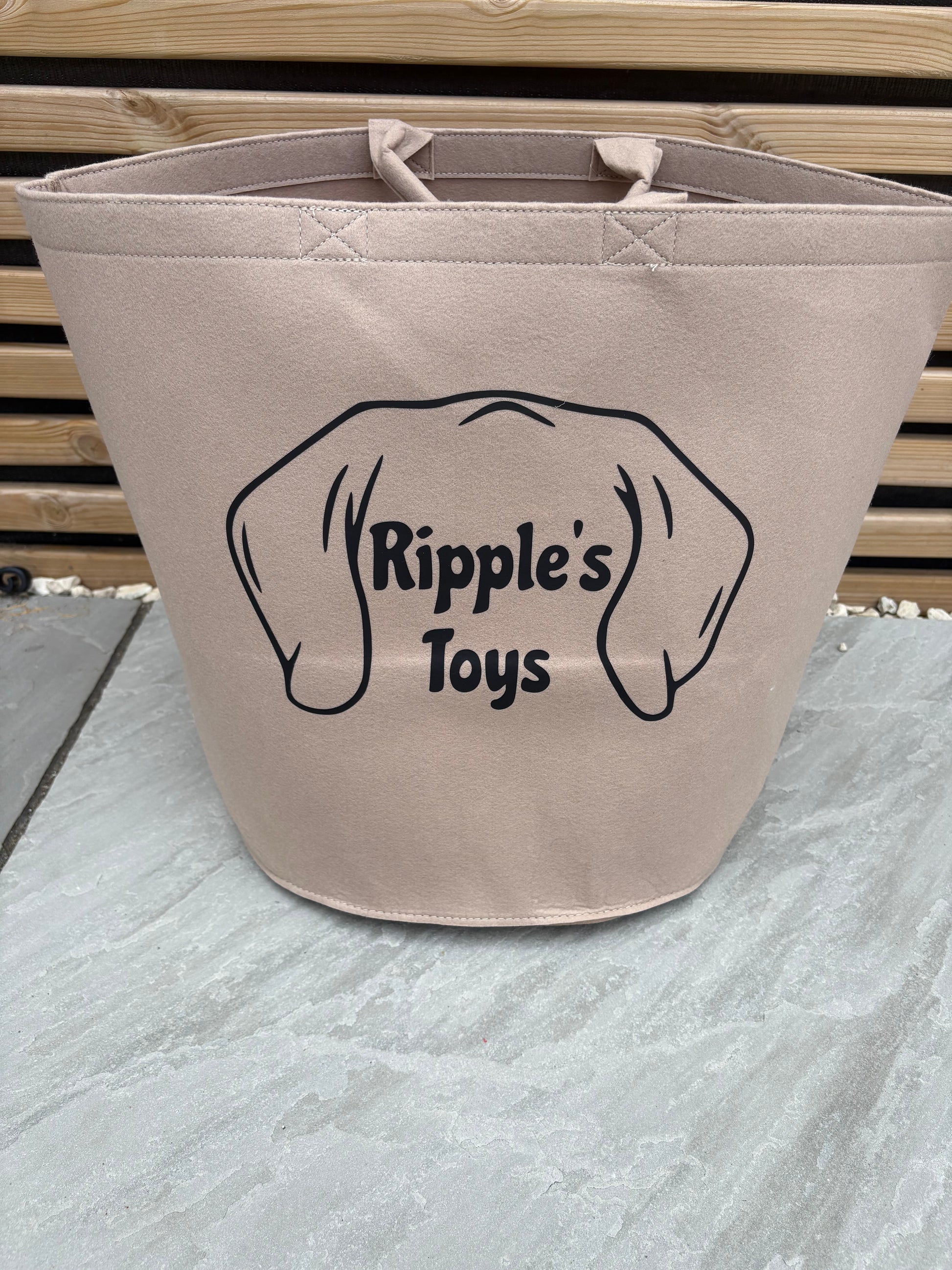 Beige bag with 'Ripple's Toys' logo on a textured wall background