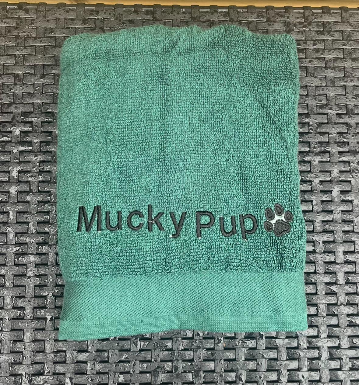 Green towel with 'Mucky Pup' logo on a textured surface