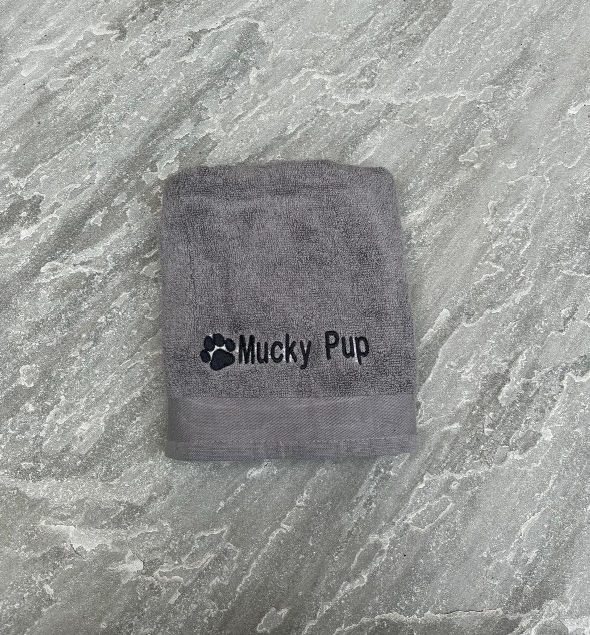 Gray towel with 'Mucky Pup' branding on a textured gray surface