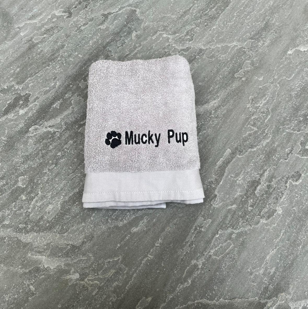 Folded towel with 'Mucky Pup' text on a textured surface