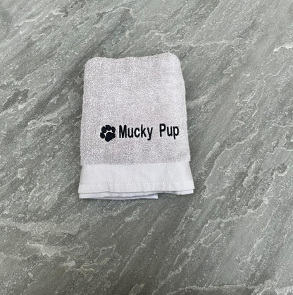 Folded towel with 'Mucky Pup' text on a textured surface