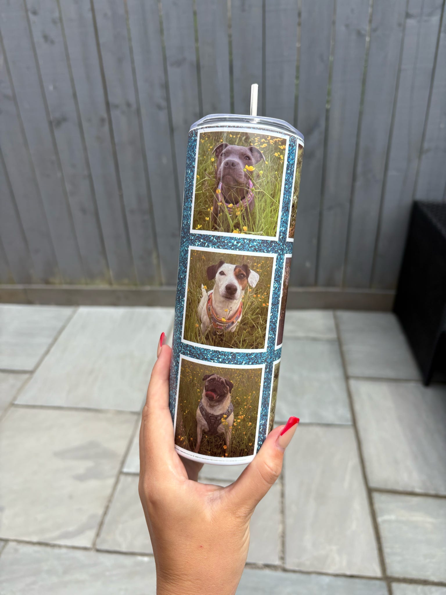 Tumbler with a collage of dog photos held by a hand on a tiled floor.