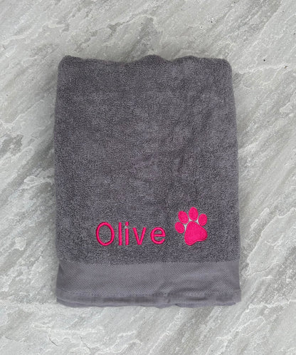 Gray towel with 'Olive' and a paw print in pink on a textured gray background