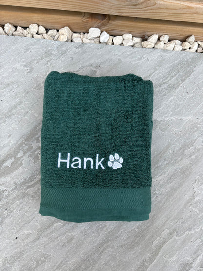 Green towel with 'Hank' and a paw print on a stone surface