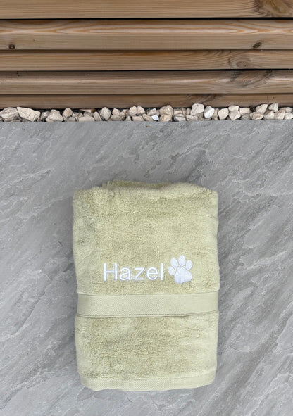 Green towel with 'Hazel' and a paw print on a stone surface
