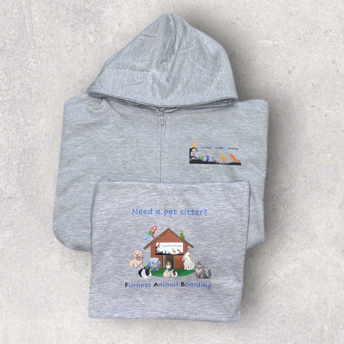 Folded gray hoodie with pet-sitting and animal boarding design on a light gray background