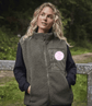 Woman wearing a green fleece gilet with a logo in a natural setting