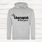 Gray hoodie with 'My therapist has paws' text on a wooden background