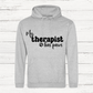 Gray hoodie with 'My therapist has paws' text on a wooden background