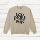 Beige sweatshirt with 'LESS people MORE Dogs' text on a wooden background
