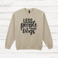Beige sweatshirt with 'LESS people MORE Dogs' text on a wooden background