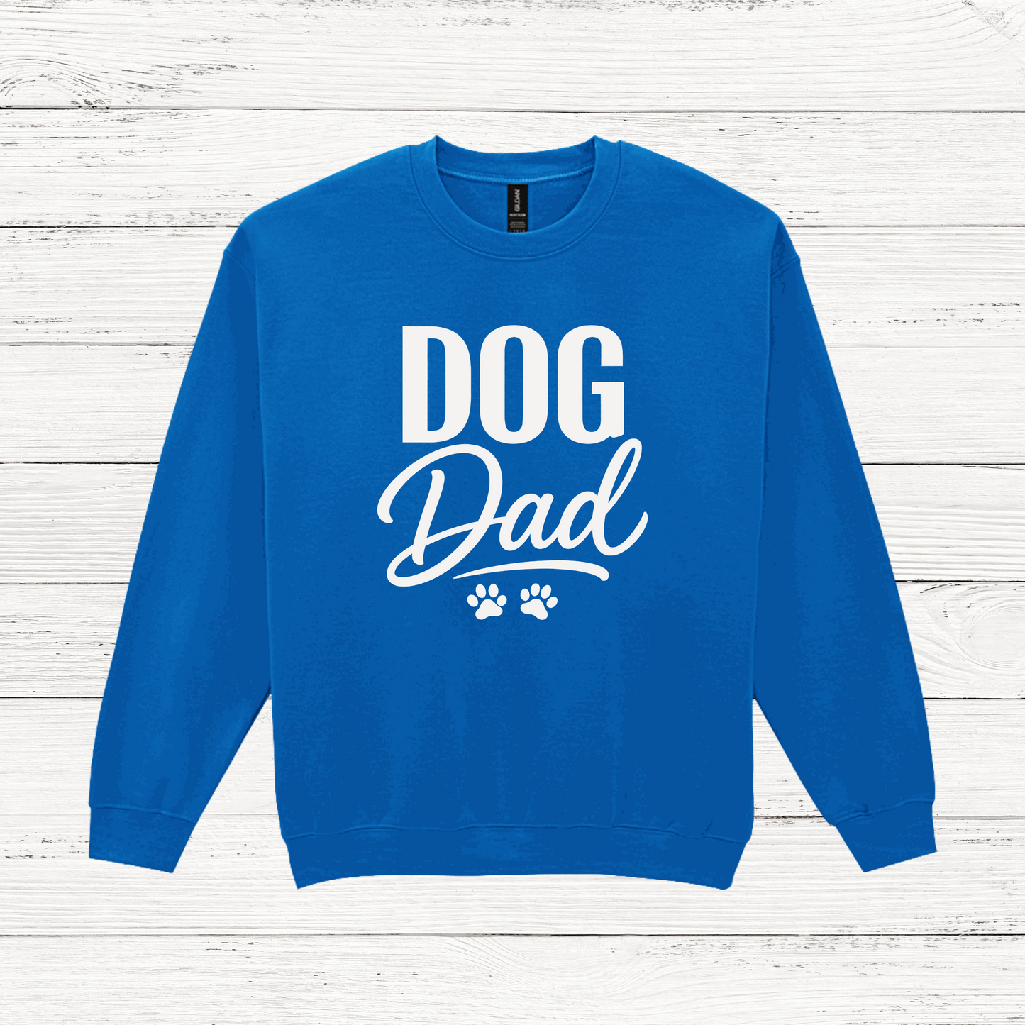 Blue sweatshirt with 'DOG Dad' text on a white wooden background