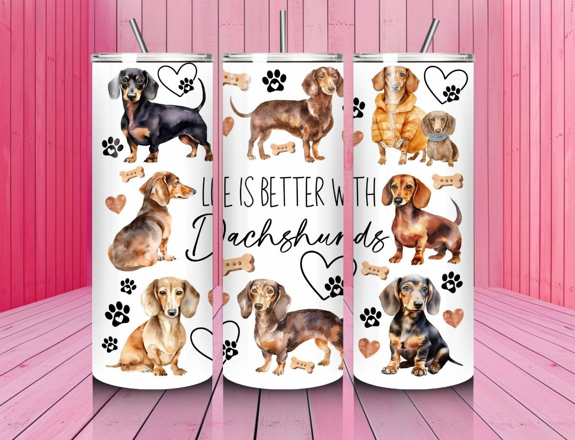 Three tumblers with dachshund designs and text on a pink wooden background